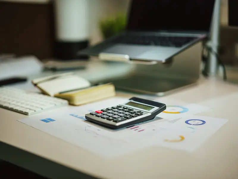 A calculator and printed charts on a desk beside a keyboard.