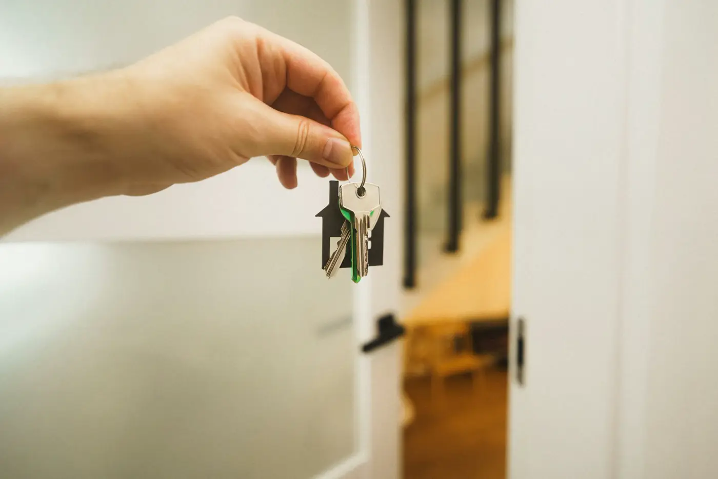 A hand holding a set of house keys in front of an open door.