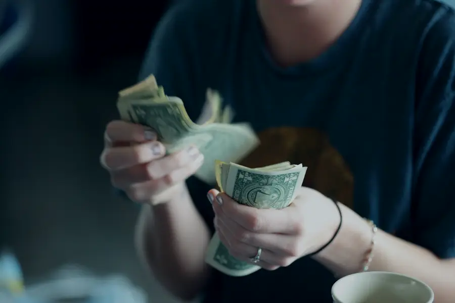 A person counting a stack of dollar bills.