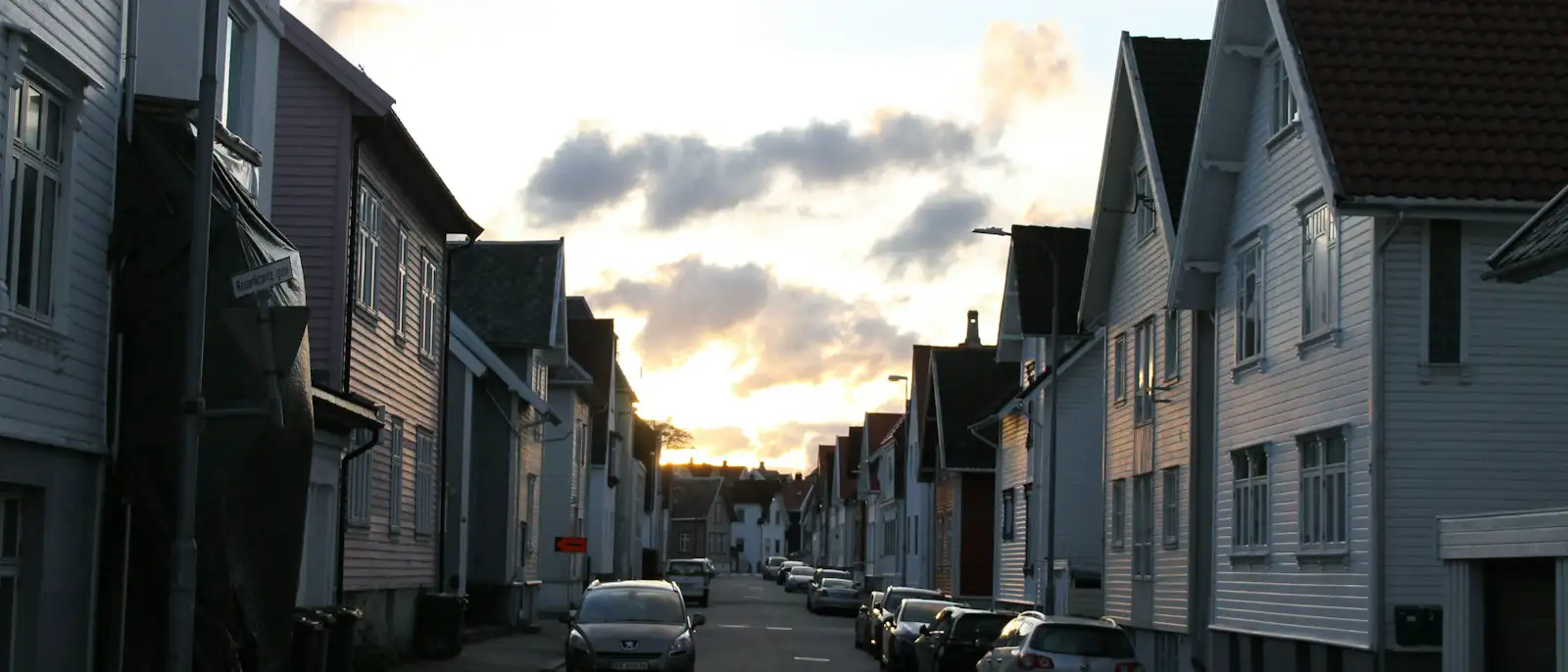 A quiet residential street of wooden houses at dusk.